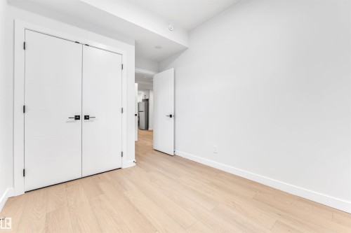 This space features light-toned hardwood flooring and crisp white walls - 10964 157 Street, Edmonton, AB - Indoor Photo Showing Other Room