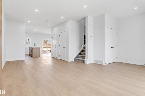 Open concept living area featuring light-toned hardwood flooring, recessed lighting, and a staircase with carpeted treads - 10964 157 Street, Edmonton, AB - Indoor