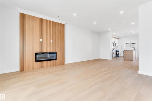 The living area features light-toned hardwood flooring, recessed lighting, and a fireplace with a slatted wooden surround - 10964 157 Street, Edmonton, AB - Indoor With Fireplace