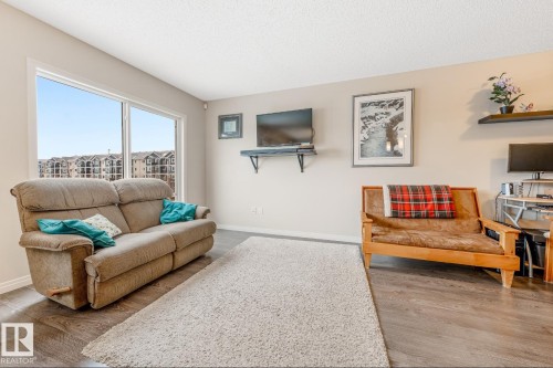 The property features a spacious living area with resilient flooring, a large window providing natural light, and neutral wall tones - 3109 Carpenter Landing, Edmonton, AB - Indoor Photo Showing Living Room