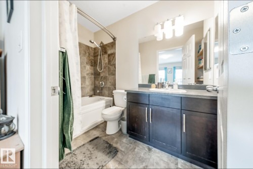 The bathroom features a vanity with a dark wood finish and a white sink, a bathtub with a shower, and tiled walls - 3109 Carpenter Landing, Edmonton, AB - Indoor Photo Showing Bathroom