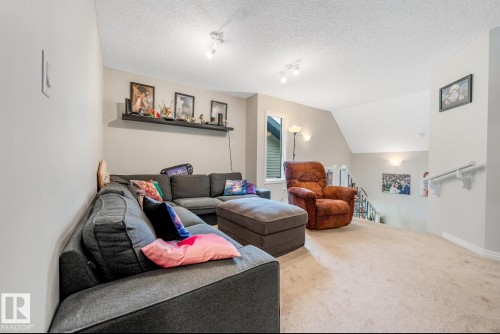 The property features a bright and spacious room with light-colored carpeting, track lighting, and a textured ceiling - 3109 Carpenter Landing, Edmonton, AB - Indoor Photo Showing Living Room