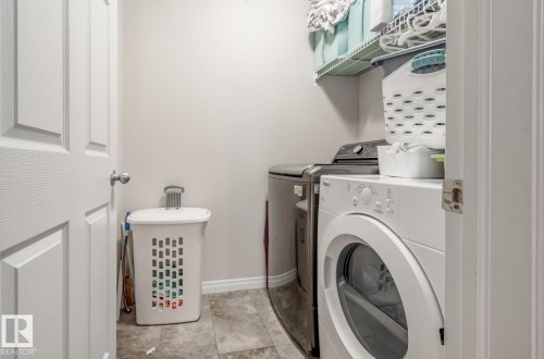 The property includes a dedicated laundry area with a washer and dryer, tiled flooring, and an overhead storage shelf - 3109 Carpenter Landing, Edmonton, AB - Indoor Photo Showing Laundry Room