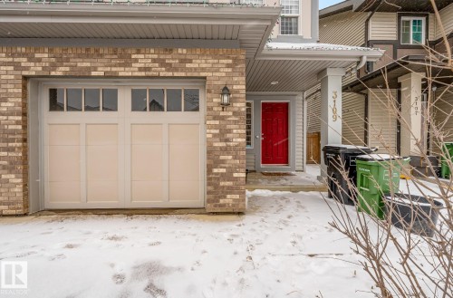 The property features a brick exterior, a garage with windows, and a prominent red front door - 3109 Carpenter Landing, Edmonton, AB - Outdoor