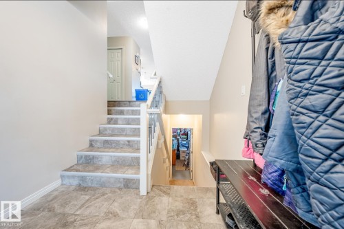 The property features a staircase with light grey tiled steps and white risers, complemented by a white handrail and balusters - 3109 Carpenter Landing, Edmonton, AB - Indoor Photo Showing Other Room