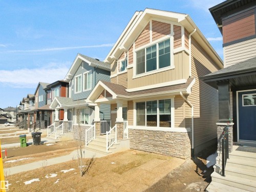 The property features a two-story design with a light beige siding and a stone facade on the lower level - 1304 14 Avenue, Edmonton, AB - Outdoor With Facade