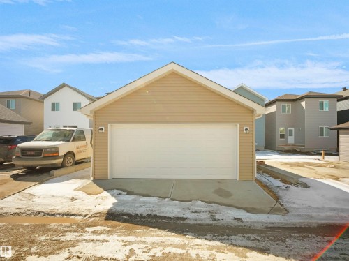 Detached garage featuring tan siding and a white garage door, with a concrete driveway approach - 1304 14 Avenue, Edmonton, AB - Outdoor