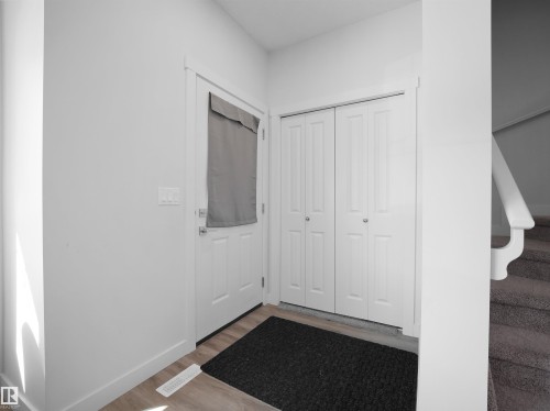The entry features a white door, light wood flooring, and a closet with bifold doors - 1304 14 Avenue, Edmonton, AB - Indoor Photo Showing Other Room
