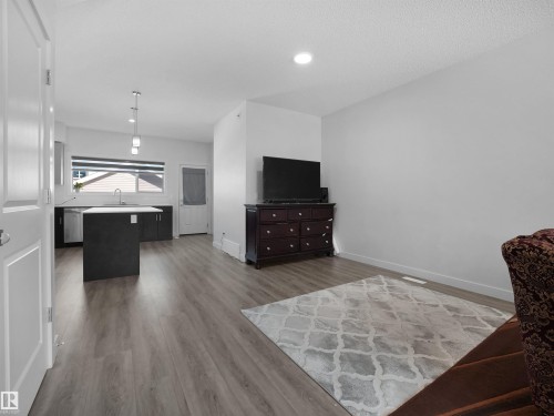 Open concept living area featuring hardwood-style flooring and a modern kitchen with a central island - 1304 14 Avenue, Edmonton, AB - Indoor