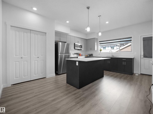 The kitchen features an island with a white countertop, modern pendant lighting, stainless steel appliances, and sleek cabinetry - 1304 14 Avenue, Edmonton, AB - Indoor Photo Showing Kitchen With Upgraded Kitchen