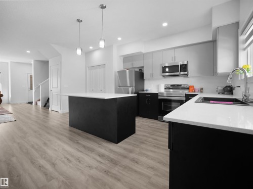 The property features a kitchen with light grey upper cabinetry, dark lower cabinetry, and light countertops - 1304 14 Avenue, Edmonton, AB - Indoor Photo Showing Kitchen With Stainless Steel Kitchen With Upgraded Kitchen