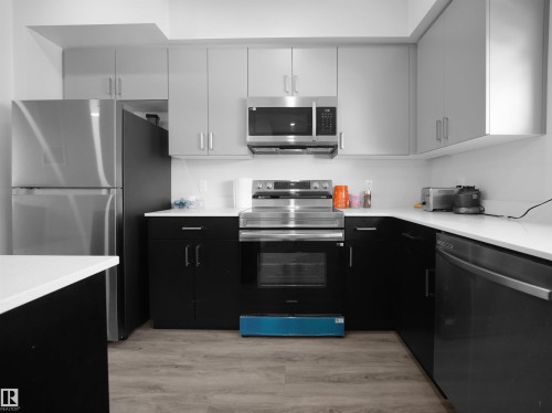The kitchen features stainless steel appliances, including a refrigerator, microwave, and oven - 1304 14 Avenue, Edmonton, AB - Indoor Photo Showing Kitchen