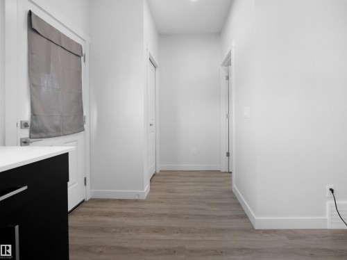 This interior hallway features wood-look flooring, white baseboards, and white walls - 1304 14 Avenue, Edmonton, AB - Indoor Photo Showing Other Room