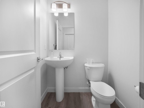 Bathroom featuring a pedestal sink, a toilet, a mirror, and a wall-mounted light fixture - 1304 14 Avenue, Edmonton, AB - Indoor Photo Showing Bathroom
