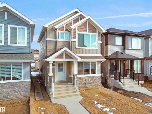 The property features a charming exterior with a covered porch, stone accents, and a front yard - 1304 14 Avenue, Edmonton, AB - Outdoor With Facade