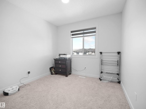 This room features light-colored carpeting, white walls, and a window providing natural light - 1304 14 Avenue, Edmonton, AB - Indoor Photo Showing Other Room