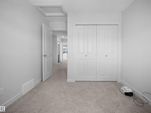 This interior space features light-colored walls, neutral carpeting, and a white bi-fold closet with panel detailing - 1304 14 Avenue, Edmonton, AB - Indoor