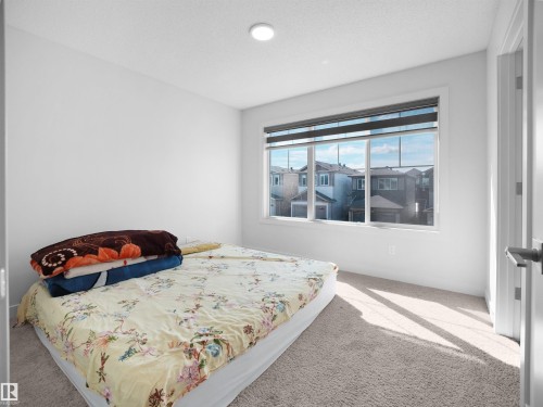 This room features white walls, light-colored carpet flooring, and a large window providing views of the neighborhood - 1304 14 Avenue, Edmonton, AB - Indoor Photo Showing Bedroom