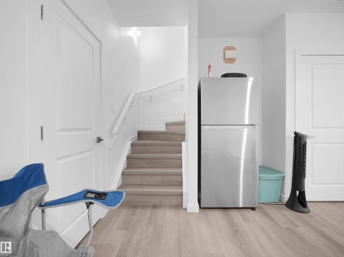 Well-lit interior space featuring light-toned flooring, white walls, and a staircase with a white railing - 1304 14 Avenue, Edmonton, AB - Indoor Photo Showing Other Room