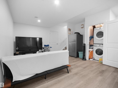 The property features light-colored flooring throughout, a laundry area with stacked appliances, and a refrigerator - 1304 14 Avenue, Edmonton, AB - Indoor Photo Showing Laundry Room