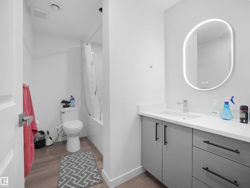 Bathroom featuring a modern vanity with a white countertop and a mirror with integrated lighting - 1304 14 Avenue, Edmonton, AB - Indoor Photo Showing Bathroom