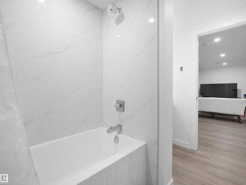 Bathroom featuring a white bathtub with a shower head and a shower faucet - 1304 14 Avenue, Edmonton, AB - Indoor Photo Showing Bathroom