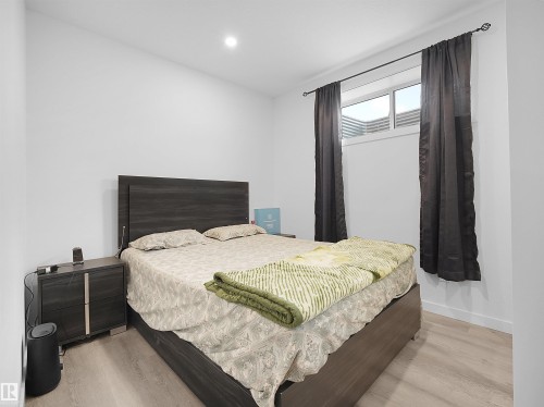 Bedroom featuring light-toned flooring, a window with dark curtains, and an overhead light fixture - 1304 14 Avenue, Edmonton, AB - Indoor Photo Showing Bedroom