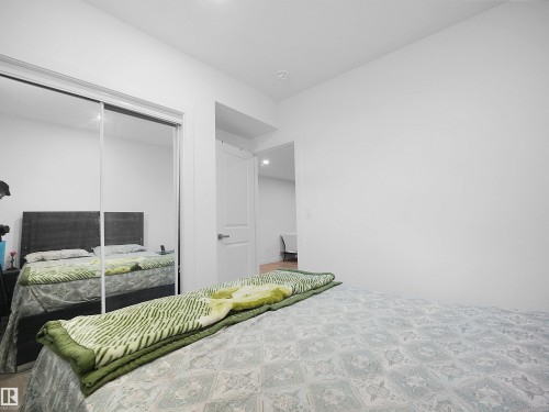 This sleeping area features white walls, a built-in closet with mirrored sliding doors, and a white door leading to another room - 1304 14 Avenue, Edmonton, AB - Indoor Photo Showing Bedroom