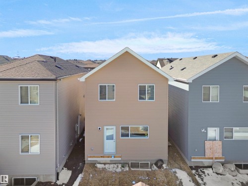 The property features tan siding, multiple windows across two levels, and a white entrance door with a small porch area - 1304 14 Avenue, Edmonton, AB - Outdoor