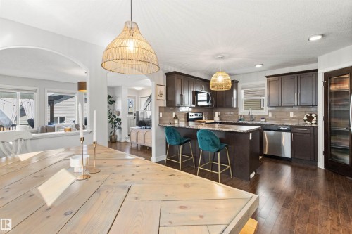 Spacious kitchen featuring dark wood cabinetry, stainless steel appliances, and a central island with bar seating - 38 Hewitt Circle, Spruce Grove, AB - Indoor