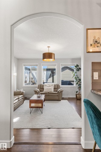 The living area features an arched entryway, three windows providing natural light, and hardwood flooring - 38 Hewitt Circle, Spruce Grove, AB - Indoor