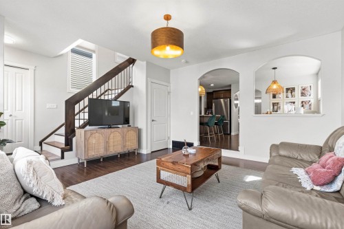 Living room featuring dark wood floors, white walls, and a staircase with dark wood banisters - 38 Hewitt Circle, Spruce Grove, AB - Indoor Photo Showing Living Room