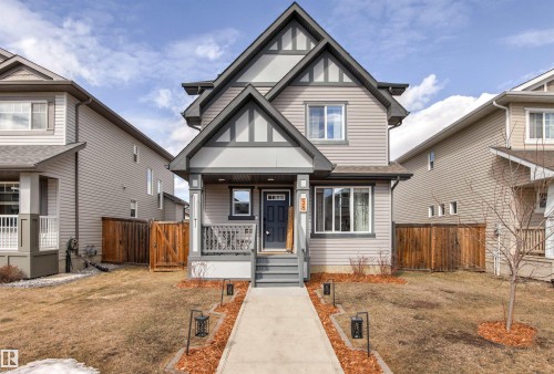 The property features a charming exterior with a covered front porch, a well-defined walkway leading to the entrance, and decorative exterior lighting - 38 Hewitt Circle, Spruce Grove, AB - Outdoor With Facade