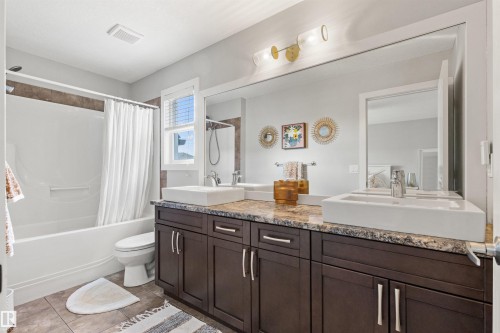 Bathroom featuring a double vanity with dark wood cabinetry, a granite countertop, and two vessel sinks - 38 Hewitt Circle, Spruce Grove, AB - Indoor Photo Showing Bathroom