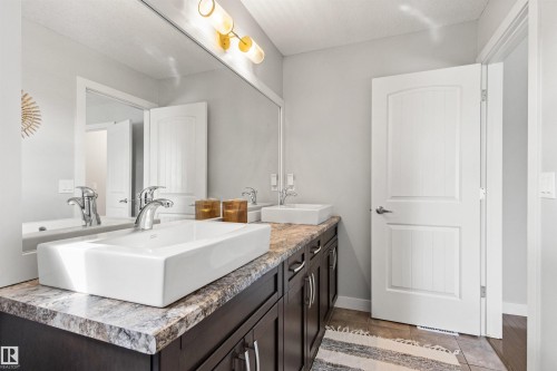 Bathroom featuring a spacious vanity with two vessel sinks, chrome faucets, and a large mirror - 38 Hewitt Circle, Spruce Grove, AB - Indoor Photo Showing Bathroom