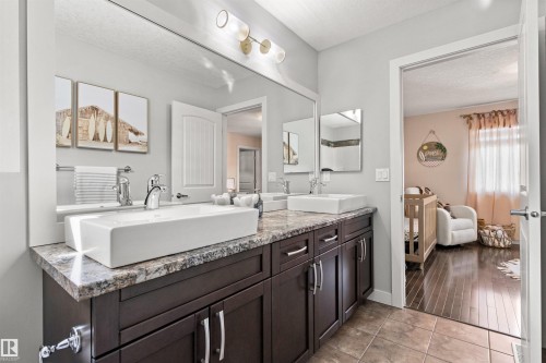 Bathroom with a vanity featuring two vessel sinks, a granite countertop, and dark wood cabinetry - 38 Hewitt Circle, Spruce Grove, AB - Indoor Photo Showing Bathroom