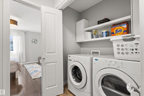 Laundry area featuring a front-load washer and dryer, with shelving and cabinetry for storage - 38 Hewitt Circle, Spruce Grove, AB - Indoor Photo Showing Laundry Room
