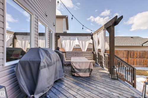 The property features an outdoor deck with wooden flooring, a wooden pergola with white fabric accents, and string lighting - 38 Hewitt Circle, Spruce Grove, AB - Outdoor With Deck Patio Veranda With Exterior