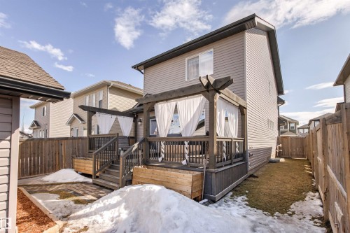 The property features a tiered wooden deck with privacy curtains, a wooden pergola, and a fenced yard - 38 Hewitt Circle, Spruce Grove, AB - Outdoor With Deck Patio Veranda With Exterior