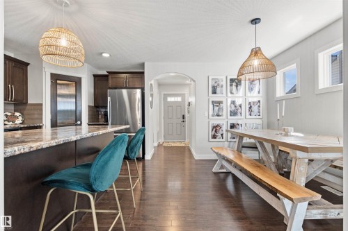 The property features rich hardwood flooring, a spacious kitchen island with a granite countertop, and dark wood cabinetry - 38 Hewitt Circle, Spruce Grove, AB - Indoor