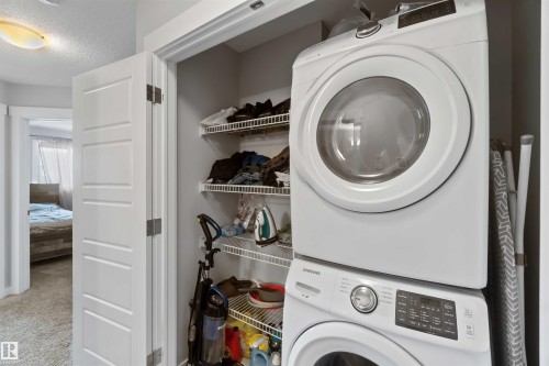 This property features a dedicated laundry area with a stacked washer and dryer, along with wire shelving for storage - 2725 Orchards Road, Edmonton, AB - Indoor Photo Showing Laundry Room