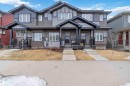 The property features a two-story exterior with a covered front porch, dark-colored siding, and white window frames - 2725 Orchards Road, Edmonton, AB  - Outdoor With Facade 