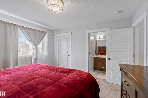 This room features a window with white curtains, a white five-panel door, and a modern ceiling light fixture - 2725 Orchards Road, Edmonton, AB - Indoor Photo Showing Bedroom