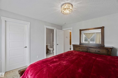This room features light gray walls, a textured ceiling, and a decorative ceiling light fixture - 2725 Orchards Road, Edmonton, AB - Indoor Photo Showing Bedroom