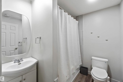 The bathroom features a white vanity with an integrated sink, a rounded mirror, and a shower with a white curtain - 2725 Orchards Road, Edmonton, AB - Indoor Photo Showing Bathroom