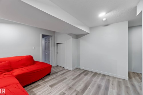 This versatile living space features light-colored walls, recessed ceiling lighting, and wood-look flooring - 2725 Orchards Road, Edmonton, AB - Indoor