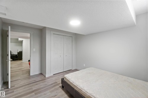 This room features light grey walls, light wood-look flooring, and a white bi-fold closet - 2725 Orchards Road, Edmonton, AB - Indoor Photo Showing Bedroom