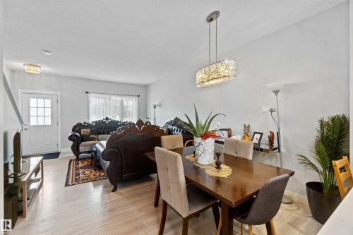 The living and dining area features light-toned flooring, light-colored walls, and a white entry door with glass panes - 2725 Orchards Road, Edmonton, AB - Indoor Photo Showing Dining Room