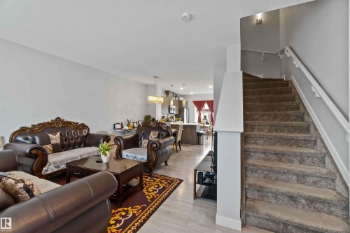Open concept living area featuring light-colored flooring, a carpeted staircase with white railings, and recessed lighting - 2725 Orchards Road, Edmonton, AB - Indoor Photo Showing Living Room