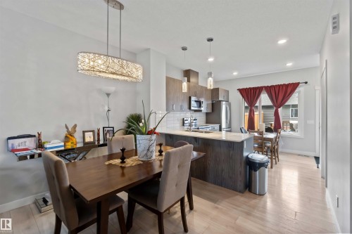 This open-concept living space features light-colored flooring, recessed lighting, and a modern chandelier - 2725 Orchards Road, Edmonton, AB - Indoor Photo Showing Dining Room